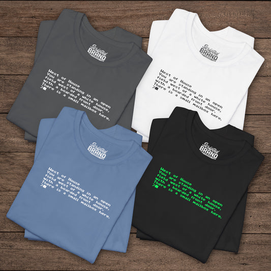 Four folded Bella+Canvas 3001 Zork “West of House” text adventure quote t-shirts with terminal-style printed text