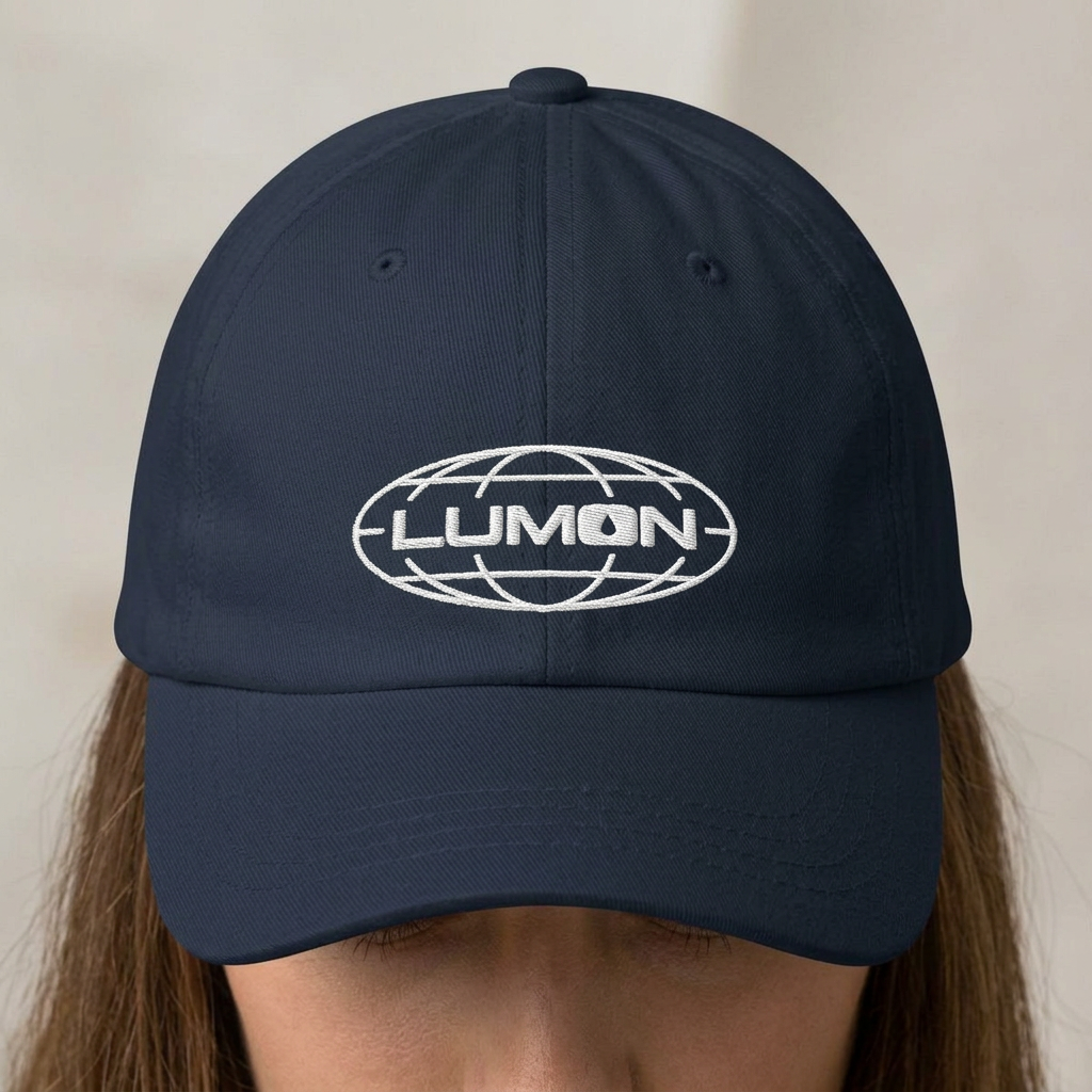 Person wearing a Navy dad hat with white embroidered Lumon Industries globe logo, Severance-inspired design cap