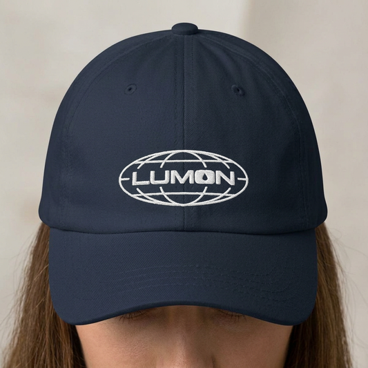 Person wearing a Navy dad hat with white embroidered Lumon Industries globe logo, Severance-inspired design cap