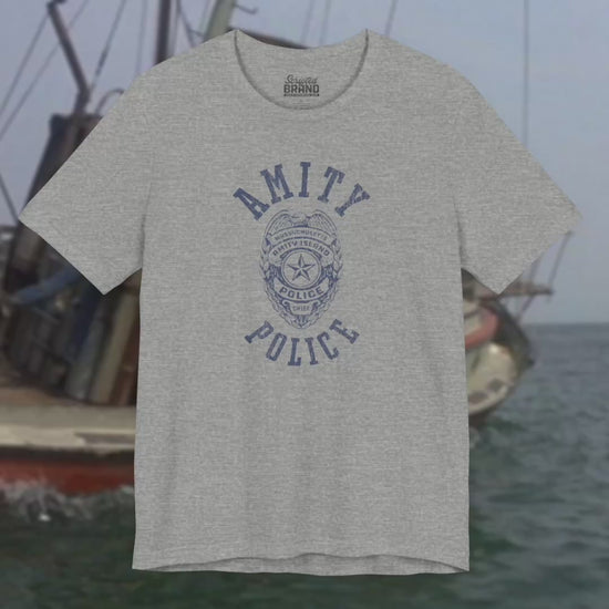 Video of Soft unisex Bella+Canvas 3001 short-sleeve t-shirts featuring an Amity Island Police logo graphic, designed by ScriptedBrand, and  inspired by the movie Jaws in a vintage distressed style.