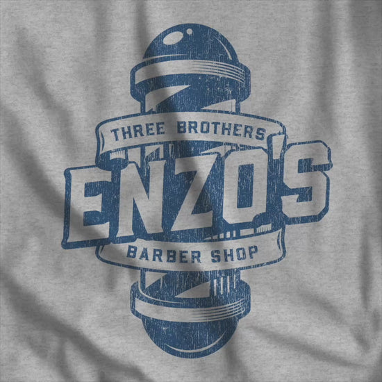 Video of athletic heather gray t-shirt with the Enzo's Barber Shop logo graphic inspired by the TV show Seinfeld in a vintage distressed style.